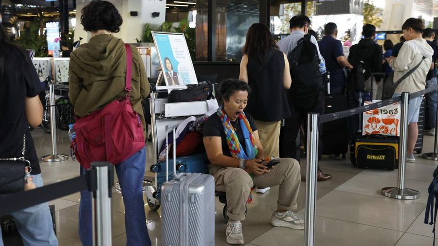 Seorang penumpang yang terlantar duduk di atas troli bagasi di area layanan pelanggan Bandara Internasional Soekarno-Hatta setelah bandara tersebut menghentikan operasionalnya akibat letusan Gunung Anak Krakatau, di Tangerang, dekat Jakarta, Indonesi