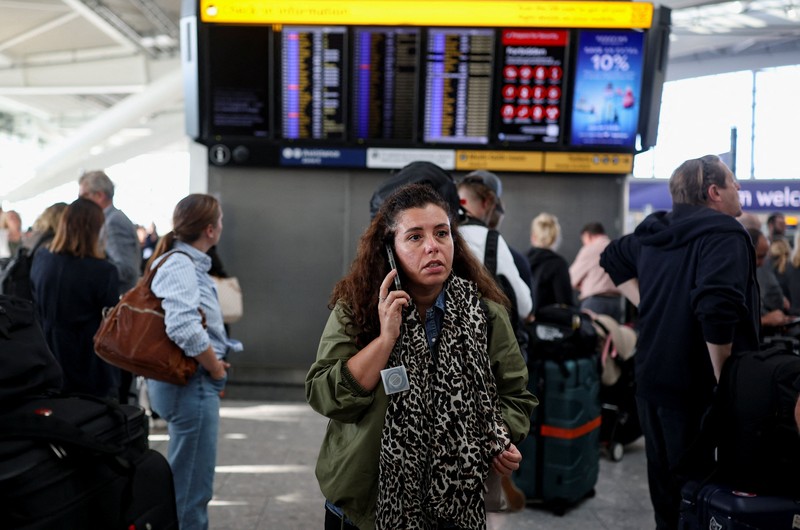Stranded passengers use their phones after some departing flights were cancelled, at Heathrow Airport's Terminal 5 in London, Britain, September 8, 2026. Some departing flights at major British airports were disrupted on Tuesday after air traffic control provider NATS experienced a technical issue, with Heathrow, Gatwick, Manchester and Stansted among the airports affected by restrictions and delays. REUTERS/Isabel Infantes