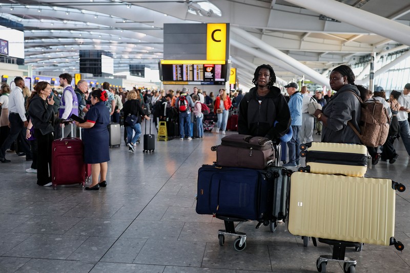 Stranded passengers use their phones after some departing flights were cancelled, at Heathrow Airport's Terminal 5 in London, Britain, September 8, 2026. Some departing flights at major British airports were disrupted on Tuesday after air traffic control provider NATS experienced a technical issue, with Heathrow, Gatwick, Manchester and Stansted among the airports affected by restrictions and delays. REUTERS/Isabel Infantes