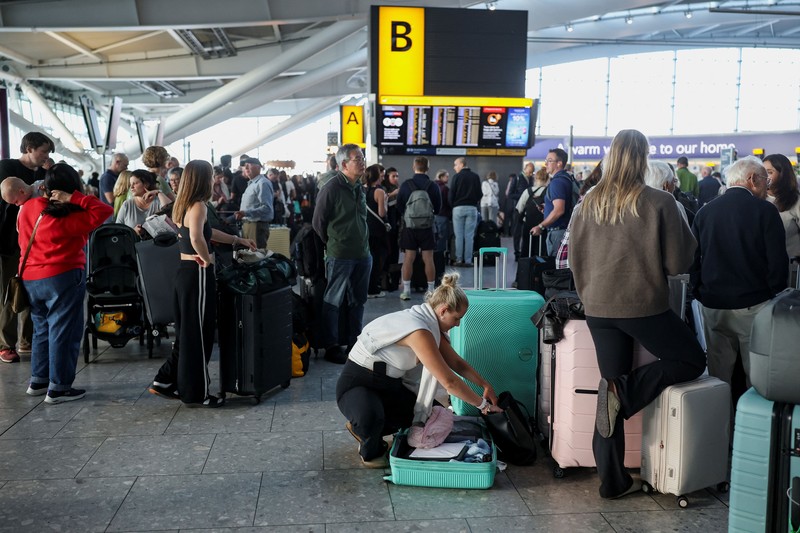 Stranded passengers use their phones after some departing flights were cancelled, at Heathrow Airport's Terminal 5 in London, Britain, September 8, 2026. Some departing flights at major British airports were disrupted on Tuesday after air traffic control provider NATS experienced a technical issue, with Heathrow, Gatwick, Manchester and Stansted among the airports affected by restrictions and delays. REUTERS/Isabel Infantes