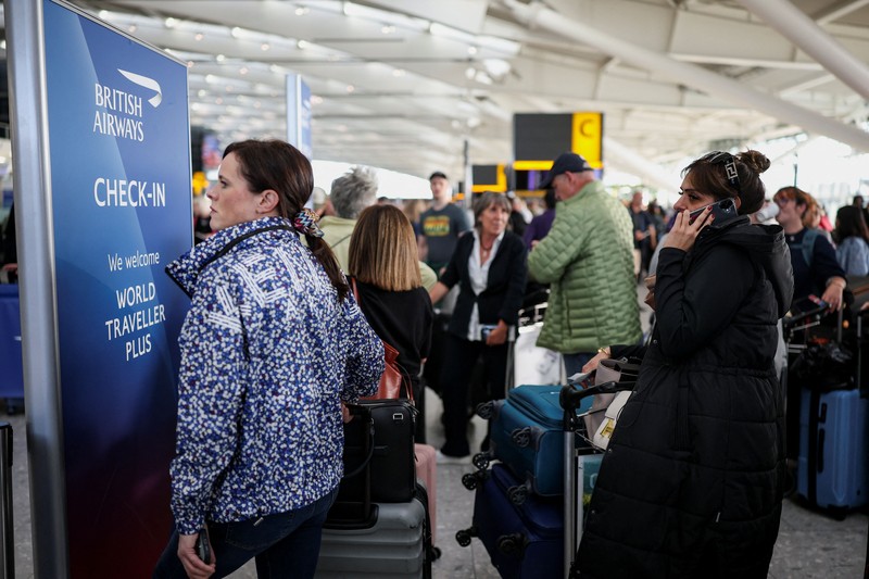 Stranded passengers use their phones after some departing flights were cancelled, at Heathrow Airport's Terminal 5 in London, Britain, September 8, 2026. Some departing flights at major British airports were disrupted on Tuesday after air traffic control provider NATS experienced a technical issue, with Heathrow, Gatwick, Manchester and Stansted among the airports affected by restrictions and delays. REUTERS/Isabel Infantes