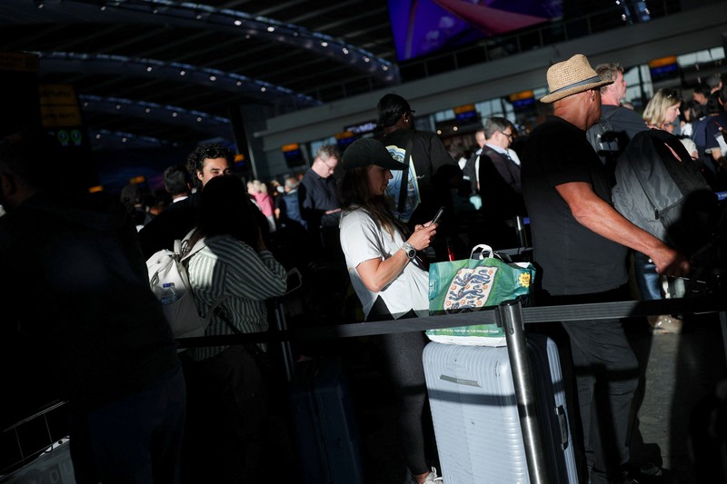 Stranded passengers use their phones after some departing flights were cancelled, at Heathrow Airport's Terminal 5 in London, Britain, September 8, 2026. Some departing flights at major British airports were disrupted on Tuesday after air traffic control provider NATS experienced a technical issue, with Heathrow, Gatwick, Manchester and Stansted among the airports affected by restrictions and delays. REUTERS/Isabel Infantes