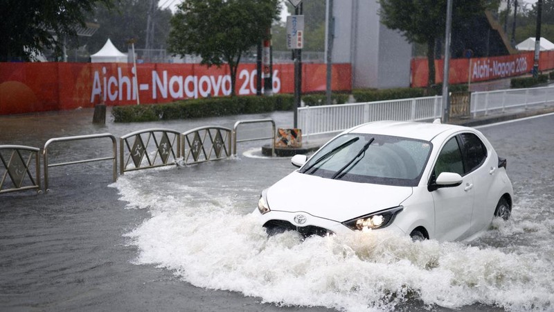 Sebuah mobil melaju di jalan yang tergenang akibat hujan deras, sementara spanduk Asian Games Aichi-Nagoya terlihat di latar belakang di Nagoya, Jepang tengah, pada 8 September 2026, dalam foto yang diambil oleh Kyodo ini. (Mandatory credit Kyodo/via