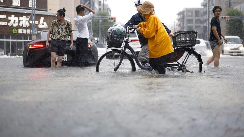 Warga melintasi jalan yang terendam banjir akibat hujan deras di Nagoya, Jepang tengah, pada 8 September 2026, dalam foto yang diambil oleh Kyodo ini.