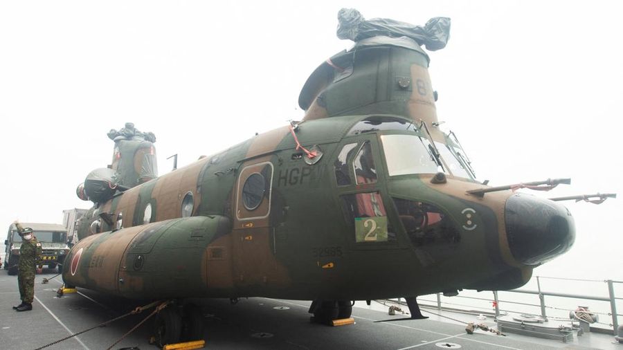 A Japanese military member stands near a Chinook helicopter on the deck of the Japanese JS Kunisaki ship, which will be used to support Indonesias efforts to fight forest fires on Kalimantan Island, in Kijing International Port, Mempawah, West Kalima