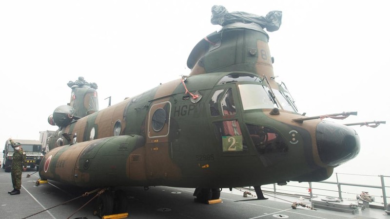 A Japanese military member stands near a Chinook helicopter on the deck of the Japanese JS Kunisaki ship, which will be used to support Indonesias efforts to fight forest fires on Kalimantan Island, in Kijing International Port, Mempawah, West Kalima
