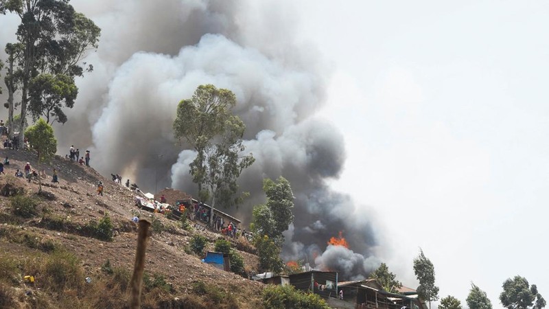 Congolese civilians gather as they attempt to extinguish fire at a school and neighbouring settlement in the area controlled by Rwanda-backed AFC/M23 rebels since the group staged an offensive in eastern Congo in February 2025, in Bukavu, Democratic