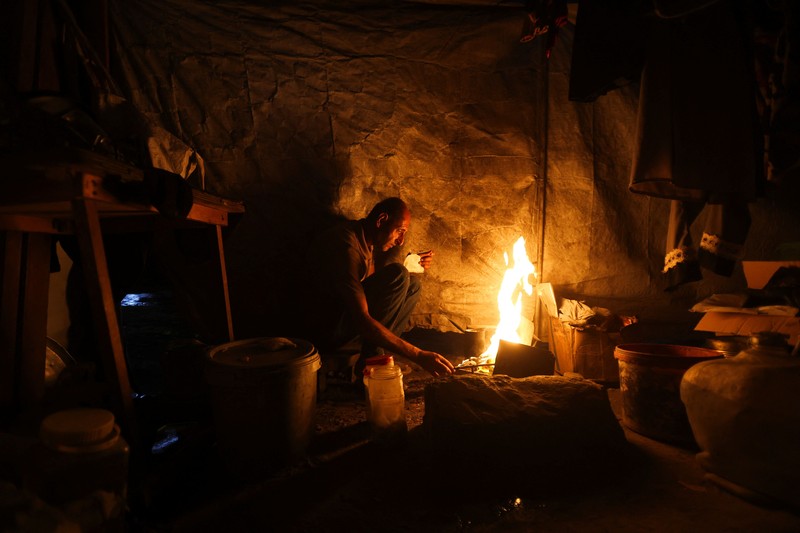 A Palestinian man lights a fire inside a tent amid shortages of electricity and fuel, in Khan Younis, in the southern Gaza Strip, September 5, 2026. REUTERS/Ramadan Abed