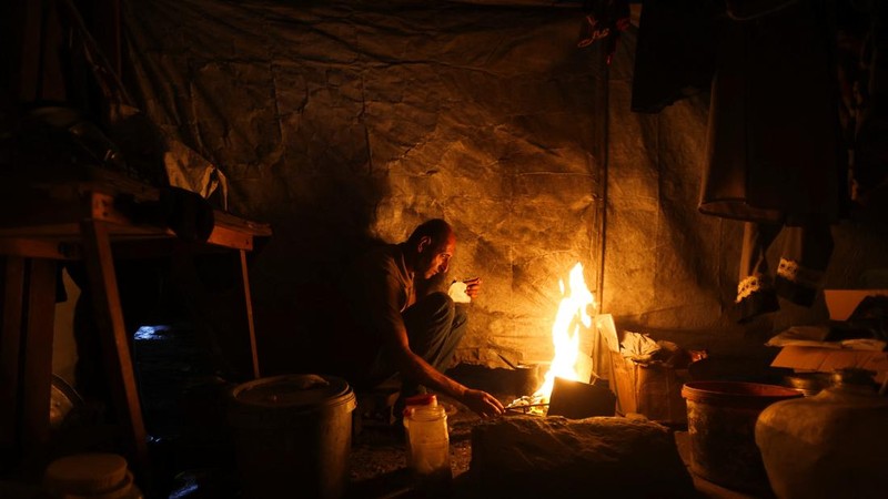 A Palestinian man lights a fire inside a tent amid shortages of electricity and fuel, in Khan Younis, in the southern Gaza Strip, September 5, 2026. REUTERS/Ramadan Abed