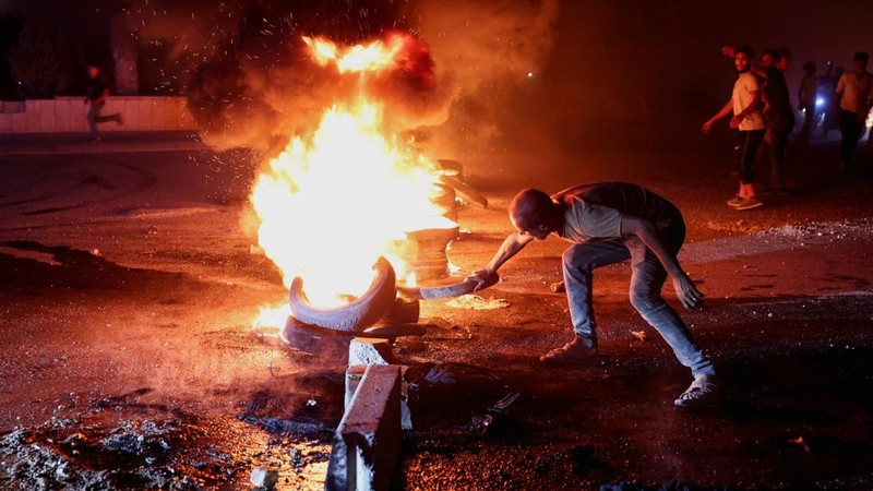 Seorang pengunjuk rasa di Aleppo membakar ban untuk memprotes kenaikan harga bahan bakar di Suriah, di jalan raya antara Aleppo dan Turki, Suriah, 13 September 2026.