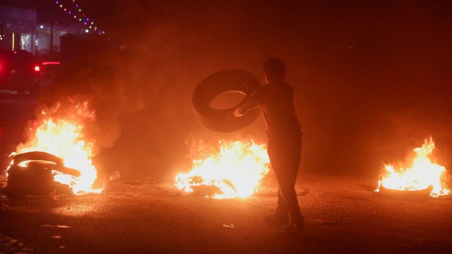 Seorang pengunjuk rasa di Aleppo membakar ban untuk memprotes kenaikan harga bahan bakar di Suriah, di jalan raya antara Aleppo dan Turki, Suriah, 13 September 2026.