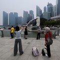 Wisatawan berfoto dengan latar belakang Merlion saat cakrawala kota diselimuti kabut asap akibat kebakaran hutan di wilayah sekitar yang mengurangi jarak pandang di seluruh negara kota kepulauan tersebut, di Singapura, 14 September 2026. (REUTERS/Suh