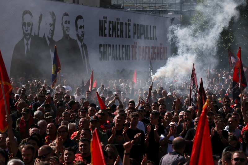 Seseorang memegang suar asap saat para pendukung mantan Presiden Kosovo Hashim Thaci berkumpul di Pristina, Kosovo, pada 16 September 2026&mdash;hari ketika Thaci dan mantan anggota Tentara Pembebasan Kosovo (KLA) lainnya mendengarkan putusan dalam sidang pengadilan kejahatan perang mereka di Kosovo Specialist Chambers di Den Haag. (REUTERS/Florion Goga)
