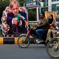 Pengendara sepeda motor melintas di dekat potret Perdana Menteri Pakistan Shehbaz Sharifyang dipasang sebagai bentuk protes terhadap kenaikan harga bahan bakar di tengah konflik AS-Iranmenjelang peluncuran nasional program pemerintah yang menawarkan