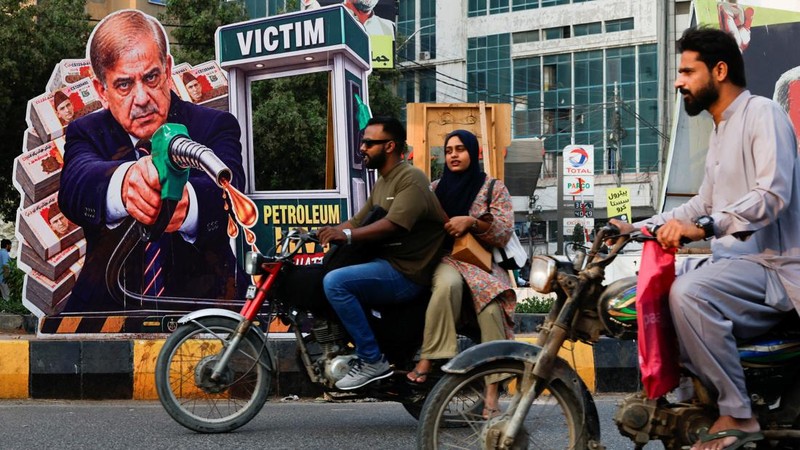 Pengendara sepeda motor melintas di dekat potret Perdana Menteri Pakistan Shehbaz Sharif—yang dipasang sebagai bentuk protes terhadap kenaikan harga bahan bakar di tengah konflik AS-Iran—menjelang peluncuran nasional program pemerintah yang menawarkan subsidi sebesar 100 Rupee per liter bagi sepeda motor, becak motor, dan kendaraan berkapasitas mesin hingga 800cc yang memenuhi syarat, di Karachi, Pakistan, 16 September 2026.