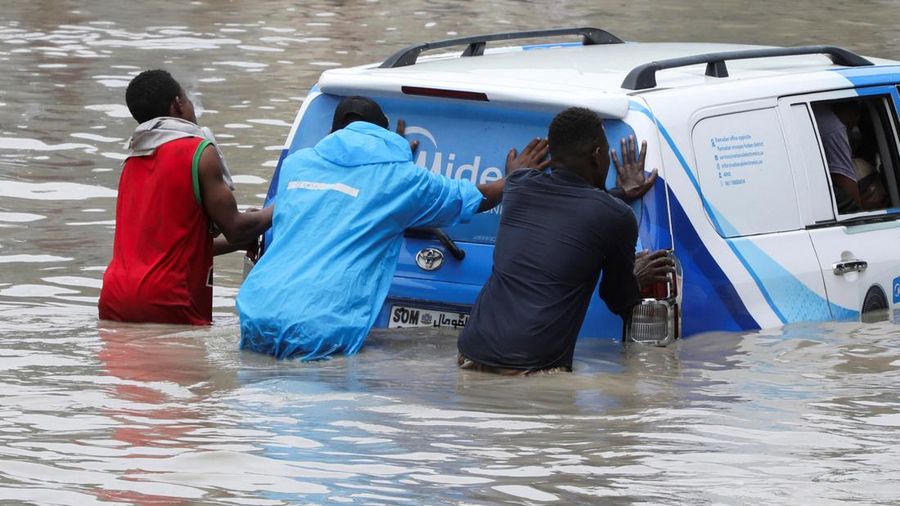 Warga mendorong mobil melewati genangan air banjir setelah hujan deras di kawasan jalan Km4 di Mogadishu, Somalia, pada 16 September 2026.