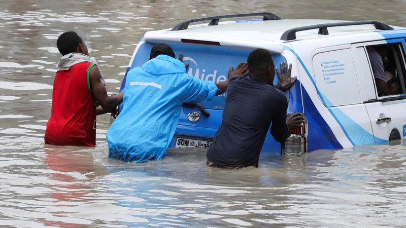Warga mendorong mobil melewati genangan air banjir setelah hujan deras di kawasan jalan Km4 di Mogadishu, Somalia, pada 16 September 2026.