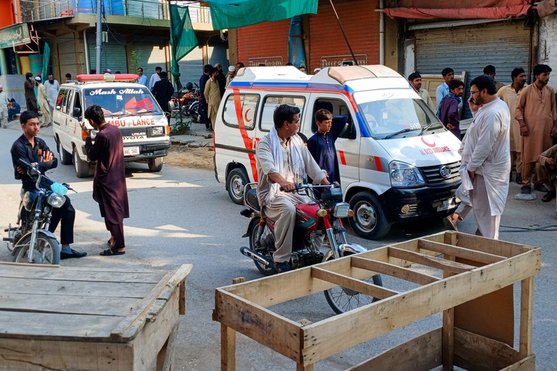 Orang-orang berdiri di dekat ambulans dan bagian fasilitas kepolisian yang rusak setelah serangan bunuh diri di Kohat, Pakistan, pada 18 September 2026. (REUTERS/Stringer)