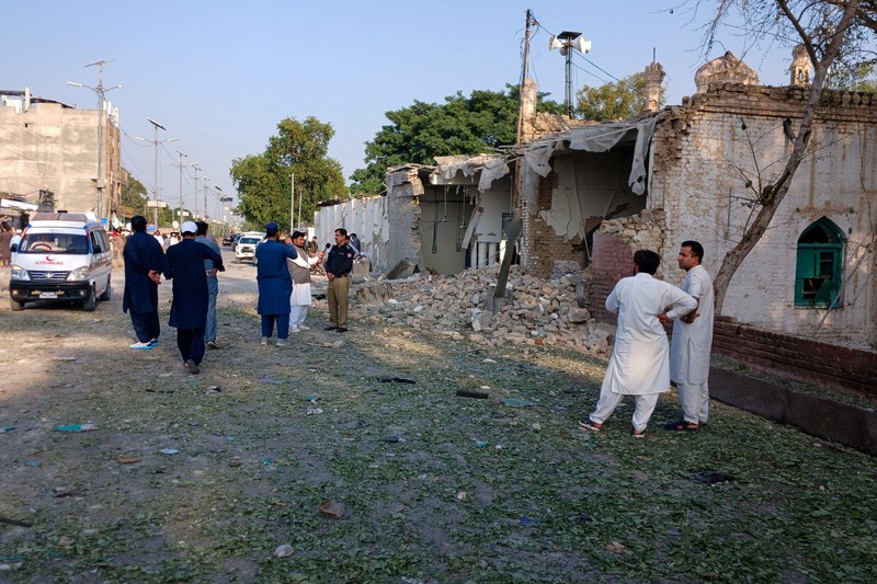 Orang-orang berdiri di dekat ambulans dan bagian fasilitas kepolisian yang rusak setelah serangan bunuh diri di Kohat, Pakistan, pada 18 September 2026. (REUTERS/Stringer)