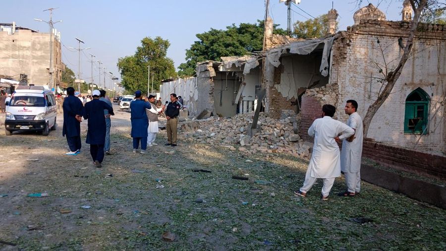 Orang-orang berdiri di dekat ambulans dan bagian fasilitas kepolisian yang rusak setelah serangan bunuh diri di Kohat, Pakistan, pada 18 September 2026. (REUTERS/Stringer)
