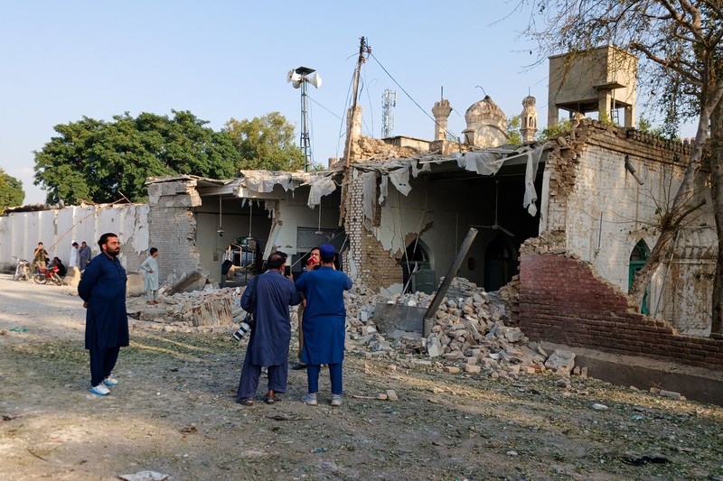 Orang-orang berdiri di dekat ambulans dan bagian fasilitas kepolisian yang rusak setelah serangan bunuh diri di Kohat, Pakistan, pada 18 September 2026. (REUTERS/Stringer)