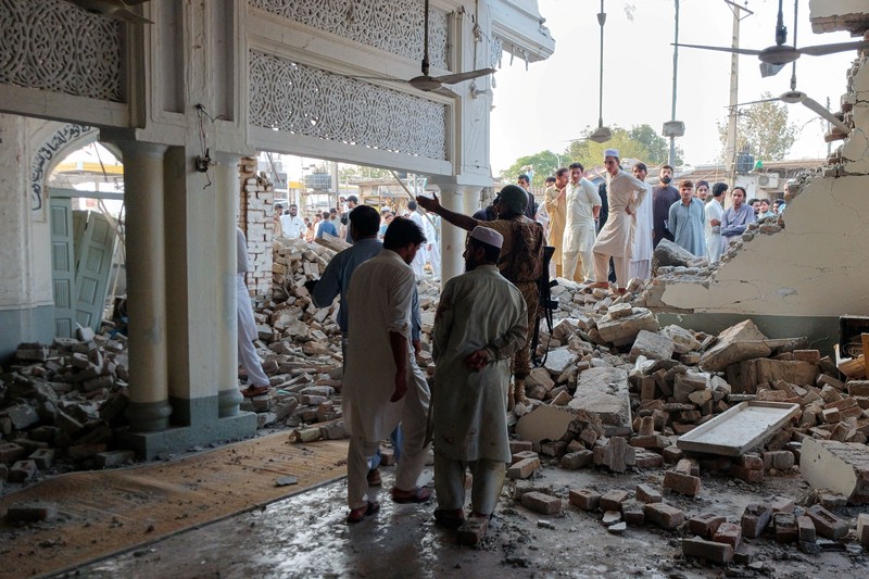Orang-orang berdiri di dekat ambulans dan bagian fasilitas kepolisian yang rusak setelah serangan bunuh diri di Kohat, Pakistan, pada 18 September 2026. (REUTERS/Stringer)