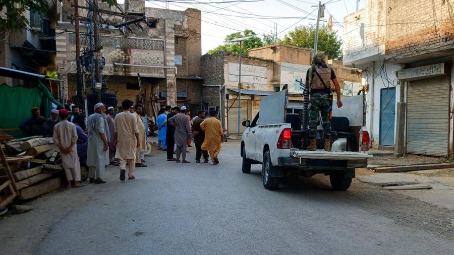 Warga dan sebuah kendaraan polisi berada di jalan setelah serangan bunuh diri di sebuah fasilitas kepolisian di Kohat, Pakistan, pada 18 September 2026. (REUTERS/Stringer)