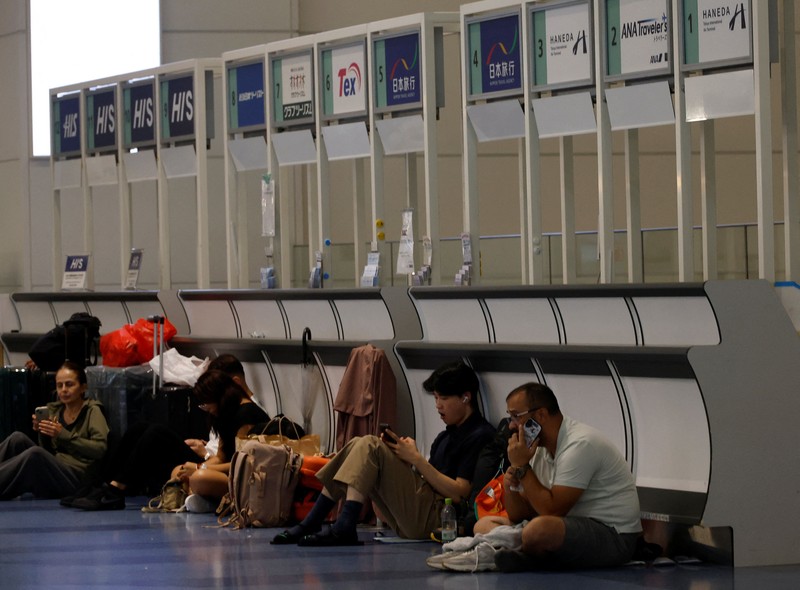 Para penumpang beristirahat di Bandara Haneda karena banyak penerbangan tertunda dan dibatalkan akibat Topan Dujuan, di Tokyo, Jepang, Senin (21/9/2026). (REUTERS/Kim Kyung-Hoon)