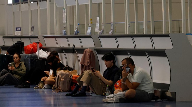 Para penumpang beristirahat di Bandara Haneda karena banyak penerbangan tertunda dan dibatalkan akibat Topan Dujuan, di Tokyo, Jepang, Senin (21/9/2026). (REUTERS/Kim Kyung-Hoon)