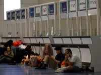 Para penumpang beristirahat di Bandara Haneda karena banyak penerbangan tertunda dan dibatalkan akibat Topan Dujuan, di Tokyo, Jepang, Senin (21/9/2026). (REUTERS/Kim Kyung-Hoon)