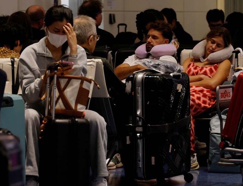 Para penumpang beristirahat di Bandara Haneda karena banyak penerbangan tertunda dan dibatalkan akibat Topan Dujuan, di Tokyo, Jepang, Senin (21/9/2026). (REUTERS/Kim Kyung-Hoon)