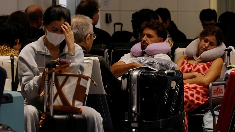 Para penumpang beristirahat di Bandara Haneda karena banyak penerbangan tertunda dan dibatalkan akibat Topan Dujuan, di Tokyo, Jepang, Senin (21/9/2026). (REUTERS/Kim Kyung-Hoon)