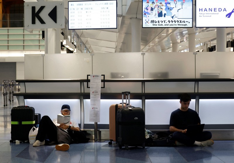 Para penumpang beristirahat di Bandara Haneda karena banyak penerbangan tertunda dan dibatalkan akibat Topan Dujuan, di Tokyo, Jepang, Senin (21/9/2026). (REUTERS/Kim Kyung-Hoon)