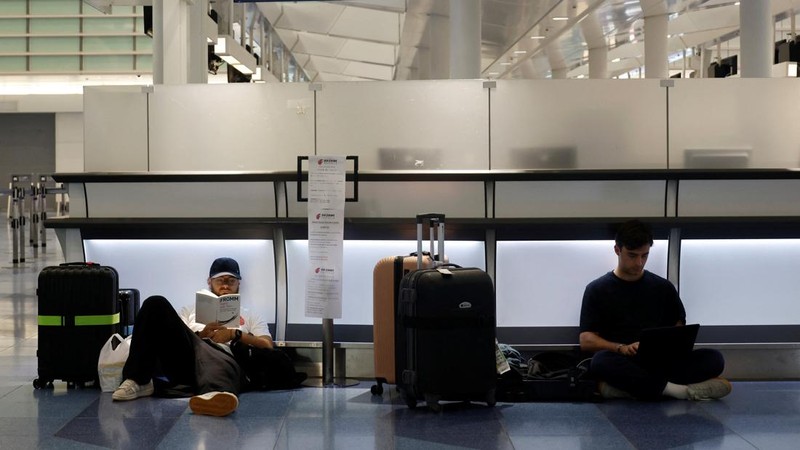 Para penumpang beristirahat di Bandara Haneda karena banyak penerbangan tertunda dan dibatalkan akibat Topan Dujuan, di Tokyo, Jepang, Senin (21/9/2026). (REUTERS/Kim Kyung-Hoon)