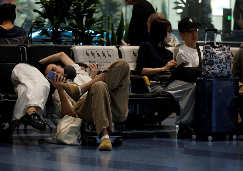 Para penumpang beristirahat di Bandara Haneda karena banyak penerbangan tertunda dan dibatalkan akibat Topan Dujuan, di Tokyo, Jepang, Senin (21/9/2026). (REUTERS/Kim Kyung-Hoon)