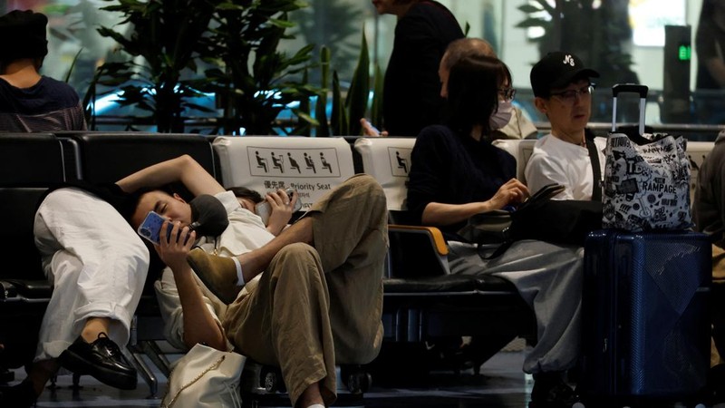 Para penumpang beristirahat di Bandara Haneda karena banyak penerbangan tertunda dan dibatalkan akibat Topan Dujuan, di Tokyo, Jepang, Senin (21/9/2026). (REUTERS/Kim Kyung-Hoon)