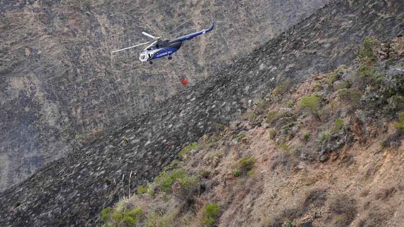 Sebuah helikopter yang membawa air terbang di atas lereng bukit yang hangus saat upaya pemadaman kebakaran hutan di Villa de Leyva, Kolombia, pada 21 September 2026.