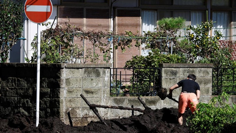 Seorang warga membersihkan lumpur di jalan dekat sebuah rumah yang tertimpa tanah longsor akibat Topan Dujuan di Miura, Prefektur Kanagawa, Jepang, pada 22 September 2026.