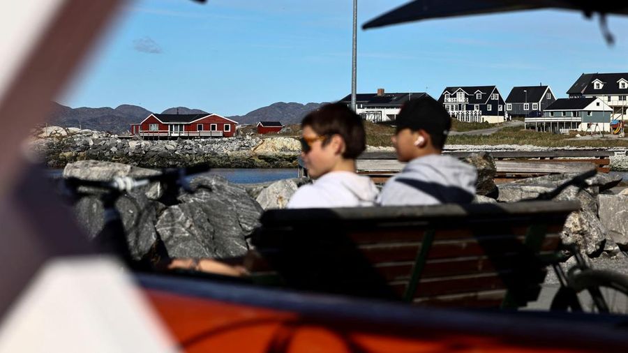 Anak-anak duduk di bangku di depan kayak di kawasan pelabuhan lama di Nuuk, Greenland, pada 22 September 2026.