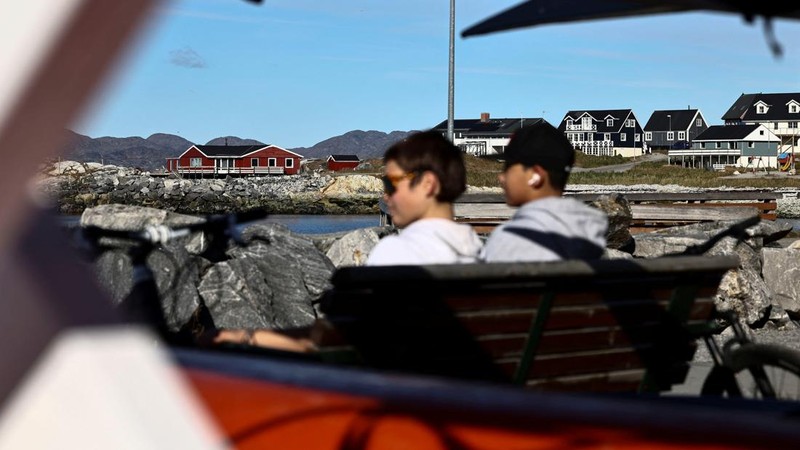 Anak-anak duduk di bangku di depan kayak di kawasan pelabuhan lama di Nuuk, Greenland, pada 22 September 2026.