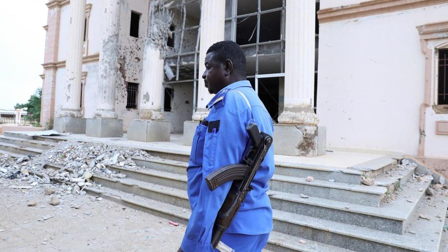 Seorang petugas polisi Sudan berjaga di depan gedung Pengadilan Kota Um Rawaba setelah serangan pesawat nirawak (drone)—yang diduga dilakukan oleh kelompok paramiliter Rapid Support Forces (RSF)—menghantam gedung pengadilan tersebut, yang merupakan pusat peradilan terkemuka, pada awal bulan ini di Kordofan Utara, Sudan, 16 September 2026.