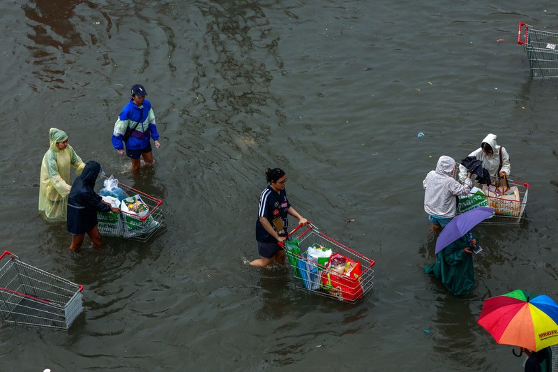People wade through a flooded street during heavy rain in Bangkok, Thailand, September 26, 2026. REUTERS/Patipat Janthong