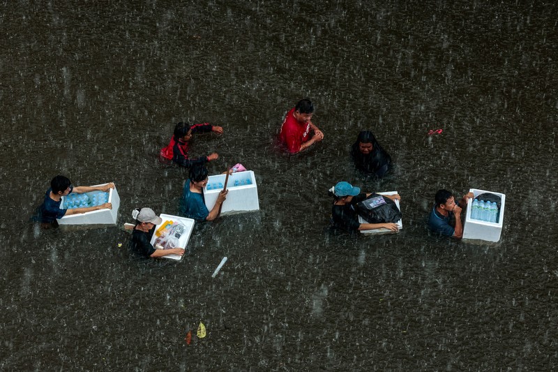 People are transported by a boat as others wade through a flooded area during heavy rain in Bangkok, Thailand, September 27, 2026. REUTERS/Patipat Janthong