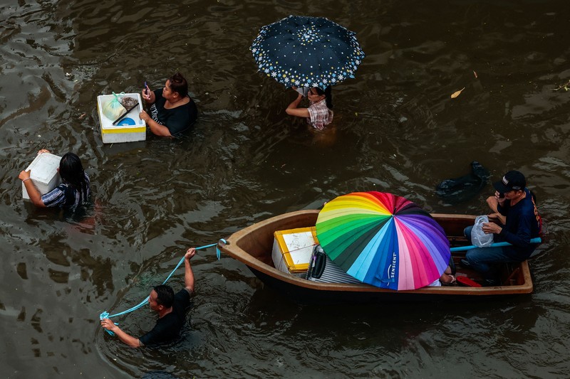 People are transported by a boat as others wade through a flooded area during heavy rain in Bangkok, Thailand, September 27, 2026. REUTERS/Patipat Janthong