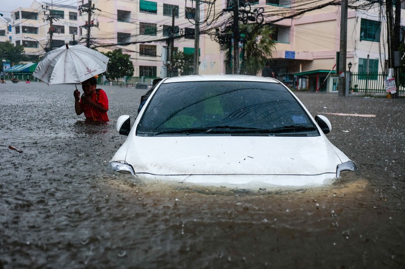 People are transported by a boat as others wade through a flooded area during heavy rain in Bangkok, Thailand, September 27, 2026. REUTERS/Patipat Janthong