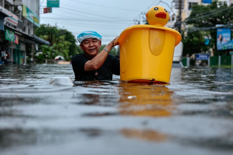 People are transported by a boat as others wade through a flooded area during heavy rain in Bangkok, Thailand, September 27, 2026. REUTERS/Patipat Janthong