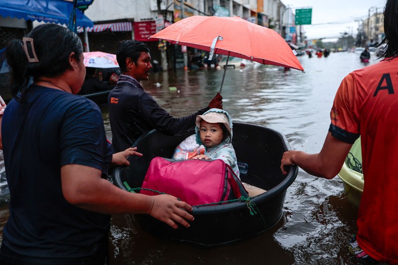 People are transported by a boat as others wade through a flooded area during heavy rain in Bangkok, Thailand, September 27, 2026. REUTERS/Patipat Janthong
