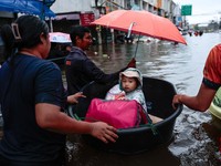 A child  sits in a plastic basin pulled by others as she is transported through a flooded area during heavy rain in Bangkok, Thailand, September 27, 2026. REUTERS/Patipat Janthong