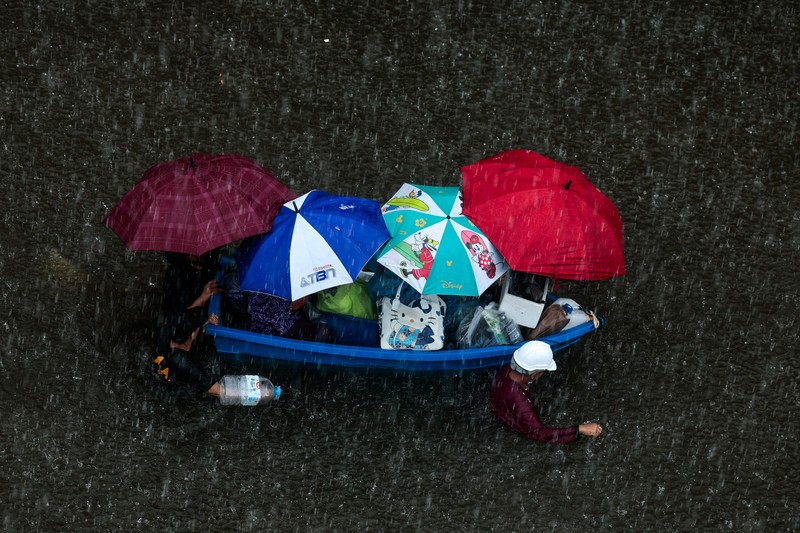 People are transported by a boat as others wade through a flooded area during heavy rain in Bangkok, Thailand, September 27, 2026. REUTERS/Patipat Janthong