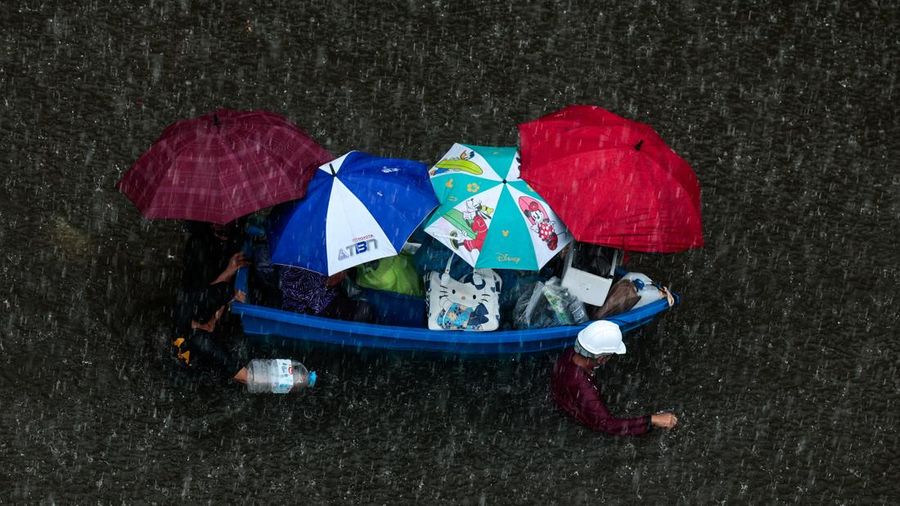 People are transported by a boat as others wade through a flooded area during heavy rain in Bangkok, Thailand, September 27, 2026. REUTERS/Patipat Janthong